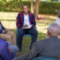 Male counsellor leading an outdoor group counselling session with elderly men in a supportive environment